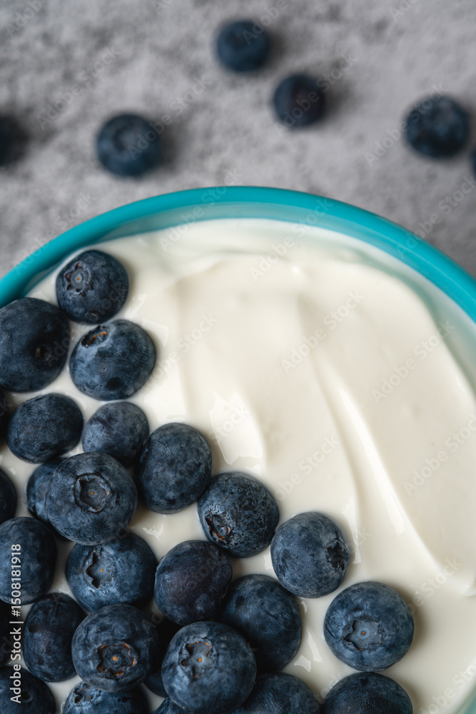 Top view of fresh blueberries on creamy yogurt in a blue bowl Top view of fresh blueberries on creamy yogurt in a blue bowl