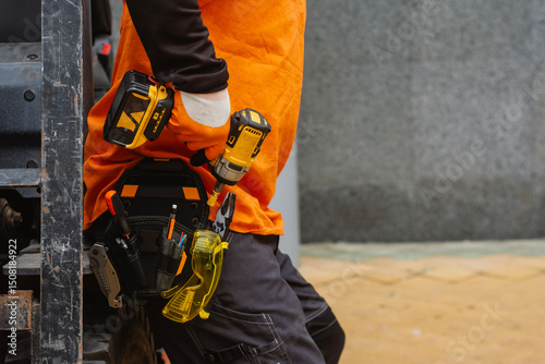 Konstfotografi Close-up of a construction worker with a tool belt, wearing protective gloves, holding a cordless drill