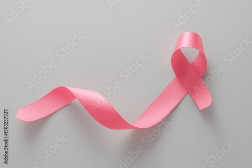 breast cancer awareness: A close-up of a pink ribbon symbolizing breast cancer awareness, laying on a light gray background, representing the fight against breast cancer and the importance of support