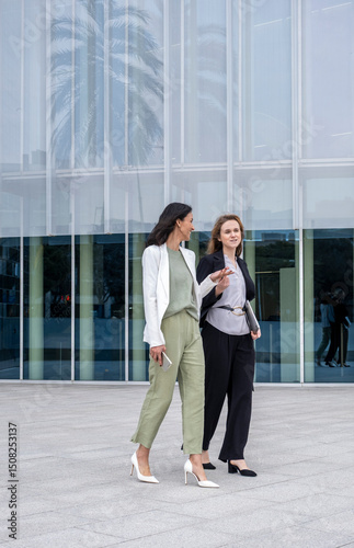 Urban setting with women talking about business opportunities, contemporary architecture, teamwork, confidence, and leadership skills