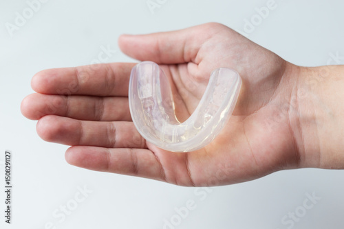 Dental silicone mouth guard for bite alignment or teeth whitening lies on a person's palm, top view, close-up