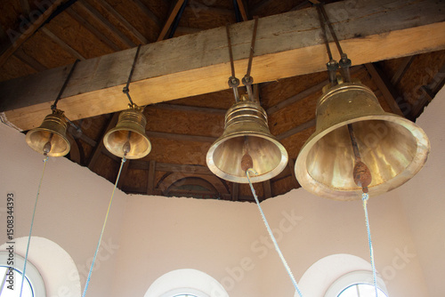 Large church bells. The bells are mounted on a wooden beam under the roof of the bell tower.
