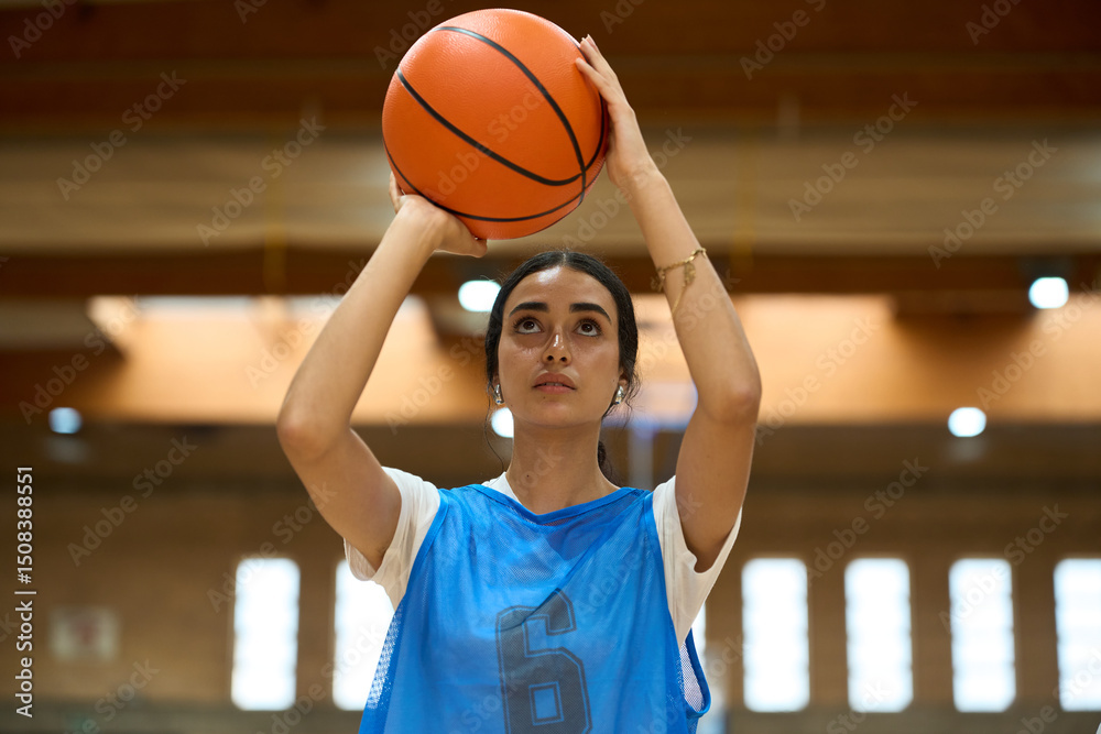 Naklejka premium Female basketball player aiming for the hoop in a gym