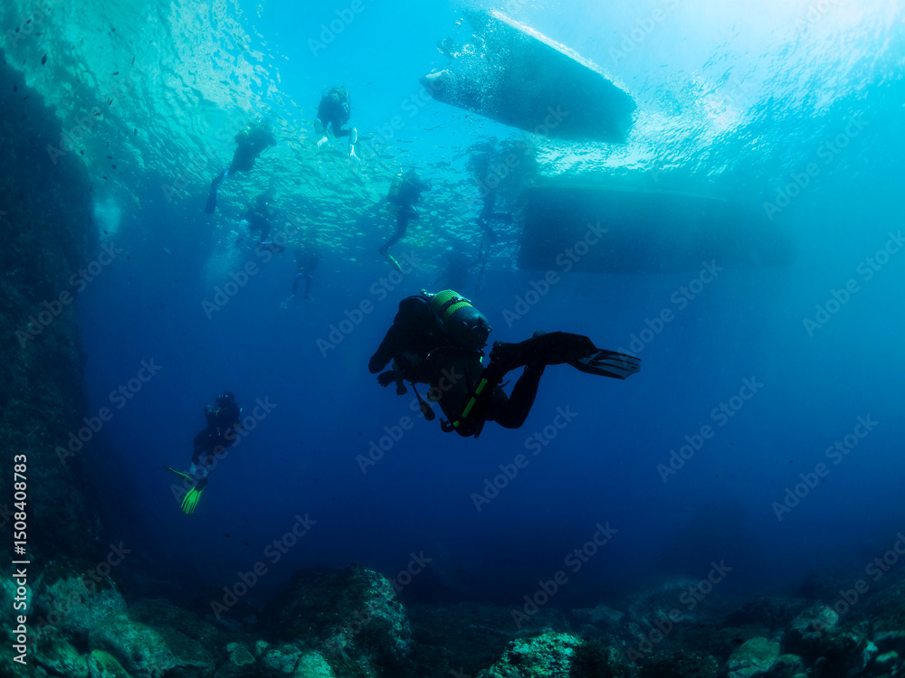 Obraz premium divers diving towards the boats on the sea surface, concept of scuba diving and underwater adventure