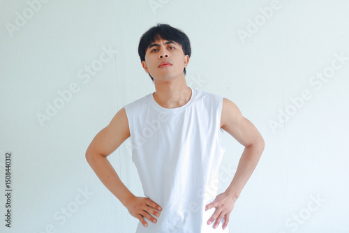 Portrait of angry young Asian man with hands on hips, showing arrogant, cocky expression. Isolated on white background, representing confidence and defiance