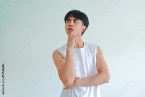 Portrait of a young Asian man from Southeast Asia with hand on chin in thoughtful pose, isolated on white background, representing thinking and contemplation