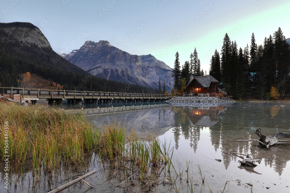 Fototapeta premium Building at the Emerald Lodge peninsula bridge end on Emerald Lake, clear dawn backed by peaks (L-R) Emerald-President-Michael. Yoho NP-BC-Canada-283