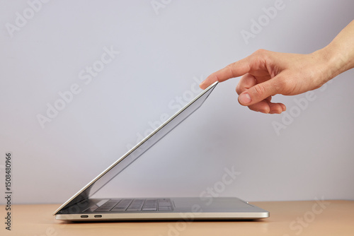 female hand open or close laptop on beige table, side view