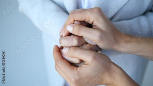 Young nurse's hands gently hold and caress the fragile hands of an elderly woman, offering comfort, reassurance, and a sense of human connection in a healthcare setting