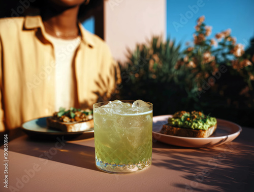 Refreshing pink cocktail with herbs on outdoor table during sunny brunch