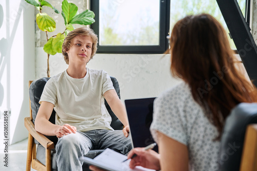Teenage boy talking to female professional psychologist counselor therapist