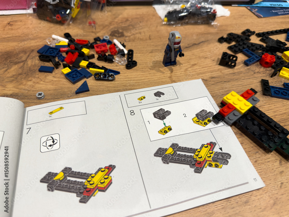 Obraz premium Moscow, Russia, April 26, 2025: LEGO Speed Champions Formula 1 Red Bull Racing car assembly in progress. Step by step building instructions, colorful bricks and driver mini figure on wooden table
