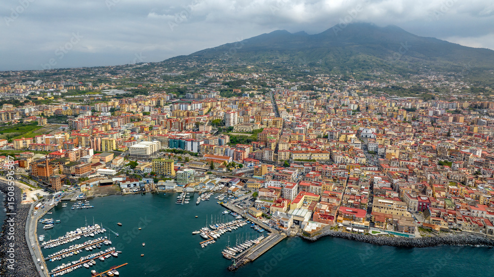 Aerial view of the city of Torre del Greco in the province of Naples, Campania, Italy. There is Mount Vesuvius in the background and the port of the town in the foreground. Aerial view of the city of Torre del Greco in the province of Naples, Campania, Italy. There is Mount Vesuvius in the background and the port of the town in the foreground.