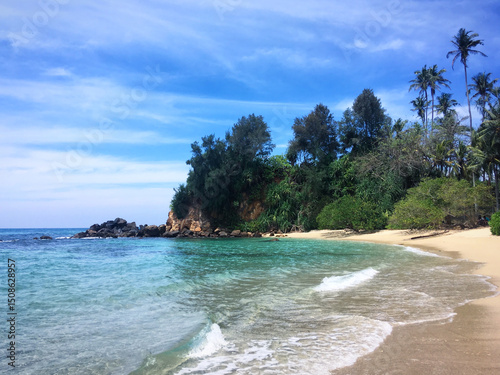 Sandy beach with turquoise waters and palm trees near Ahangama, Southern Province, Sri Lanka, March 2019