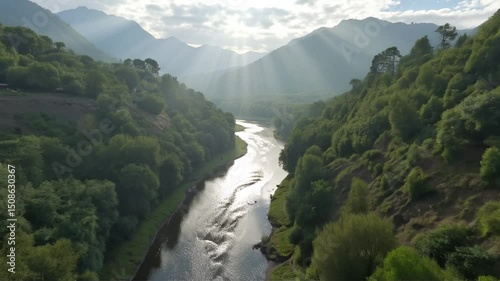 River Flowing Through Green Valley With Sun Rays Aerial View