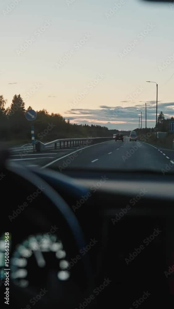 VERTICAL VIDEO: Summer road trip concept. View from a car, tourist driving along a scenic asphalted road. Scandinavian journey at sunset, Lapland in Northern Finland. Vacation, weekends, travelling.