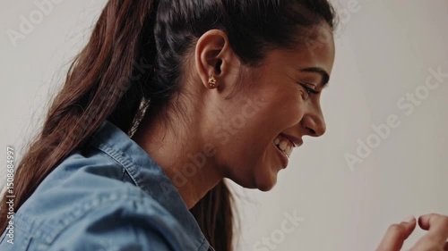 Wallpaper Mural Joyful woman in a blue denim shirt with long hair smiles warmly while adjusting a red bracelet on her wrist against a soft white background exuding happiness and style Torontodigital.ca