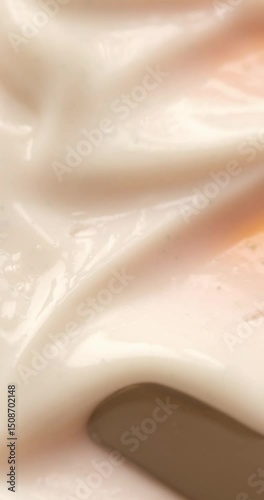 Vertical video of making skincare cosmetic product smears with metal spatula on beige background close up. Beauty abstract