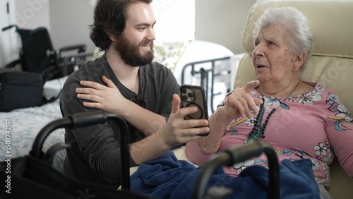 Quadro su tela Grandson smiles as he shares happy memories with his grandmother using his smartphone in a cozy room filled with warmth and love