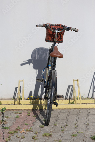 A basketed bicycle parked (locked) onto a yellow bike rack