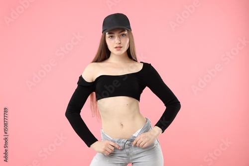 Portrait of beautiful woman in stylish baseball hat on pink background