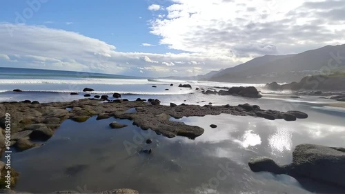 Ocean Waves Crashing on Rocky Coastline with Mountain Views