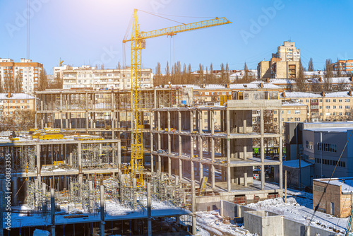 Tall building under construction with scaffolds,Freestanding tower crane on a building site.Building construction site work against blue sky