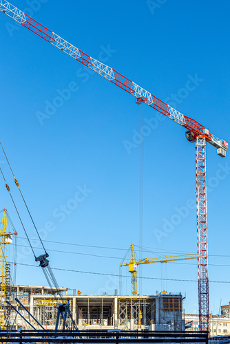 Tall building under construction with scaffolds,Freestanding tower crane on a building site.Building construction site work against blue sky