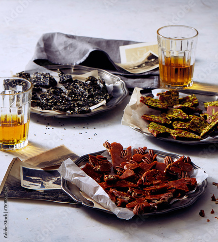 Assorted brittle varieties on metal trays with drinks and photos
