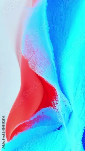 Dynamic abstract fluid paint creates flowing organic patterns mixing vibrant blue cyan and red colors in smooth artistic motion