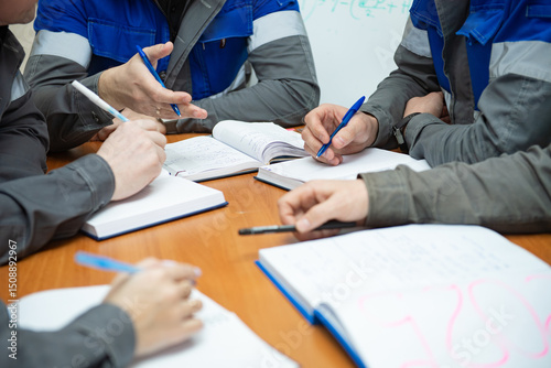 Refinery workers and engineers meeting reviewing blueprints in factory