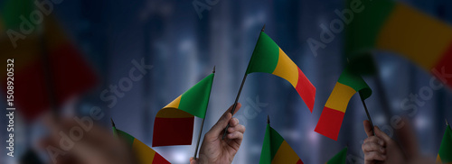 Mali flags in their hands on a blurred urban background