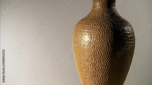 A vase with a gold pattern on a wooden top and base. photo