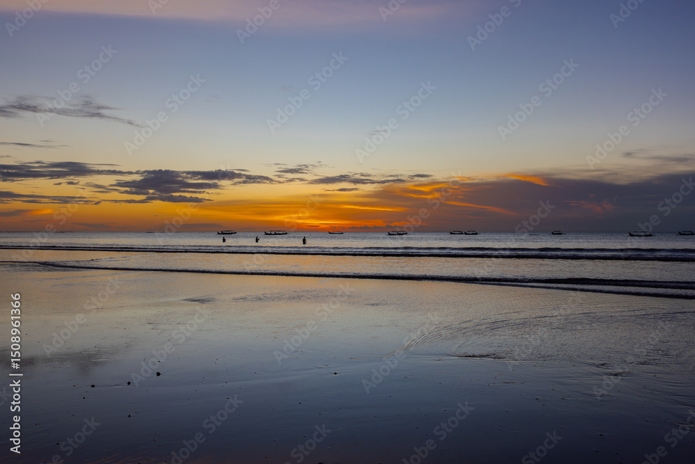 Fototapeta premium Beautiful colourful sunset on Kuta Beach on the island of Bali blue purple orange skies with turquoise blue waters and silhouette of people on the sandy beach the land of gods Bali Island Indonesia 