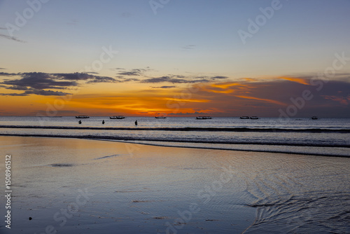 Beautiful colourful sunset on Kuta Beach on the island of Bali blue purple orange skies with turquoise blue waters and silhouette of people on the sandy beach the land of gods Bali Island Indonesia 