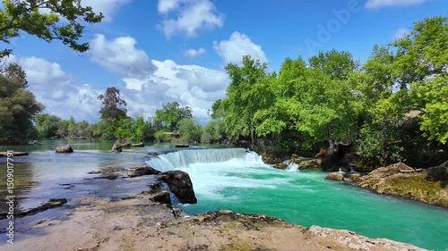 Beautiful landscape of Manavgat waterfall in national park on sunny summer day showcasing azure waterfall water splashing down wide stream from small height, slow motion
