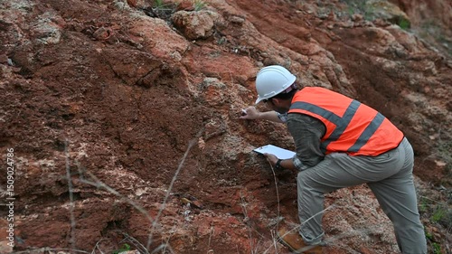 A geologist is using a steel rod to drill into a rock to obtain a rock sample for analysis