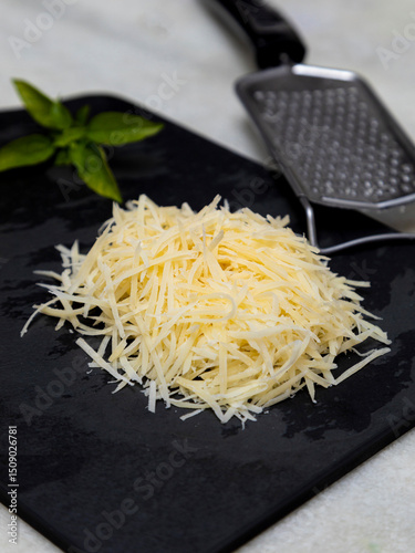 Foto Grated Parmesan cheese on black stone with garlic, onion, pepper and other spice