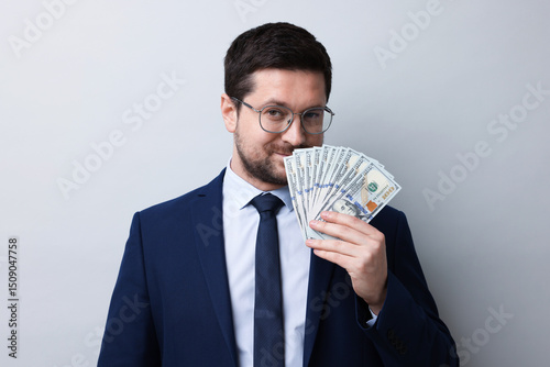 Foto Greedy banker sniffing dollar banknotes on grey background