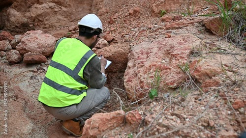 A geologist is examining the mineral content of soil and recording it on paper