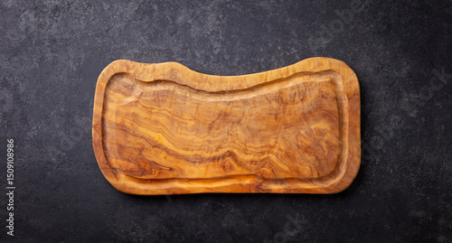 Provencal olive wood chopping board or cutting board. Dark stone background. Copy space. Close up. Top view.