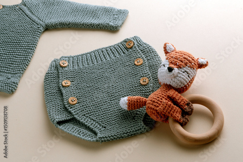 Knitted baby clothes and handmade accessories on neutral fabric in newborn outfit from above
