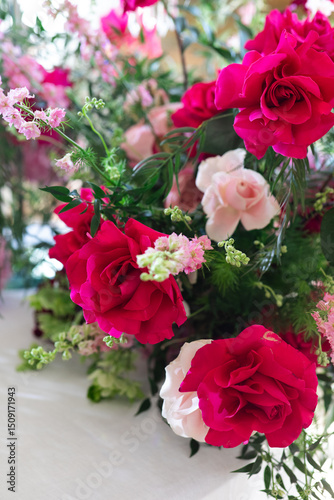 Close-up of floral arrangement with red, pink, and white roses, greenery, and small pink blossoms. Studio flower photography. Wedding floral decoration and romantic botanical concept. Design for greet