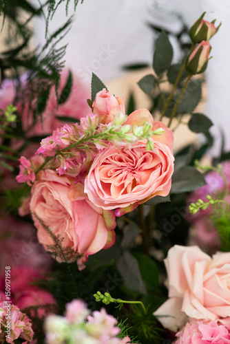 Close-up of floral arrangement with red, pink, and white roses, greenery, and small pink blossoms. Studio flower photography. Wedding floral decoration and romantic botanical concept. Design for greet