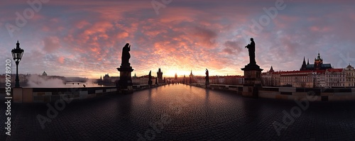Charles Bridge in Prague, with the city skyline behind it at sunrise