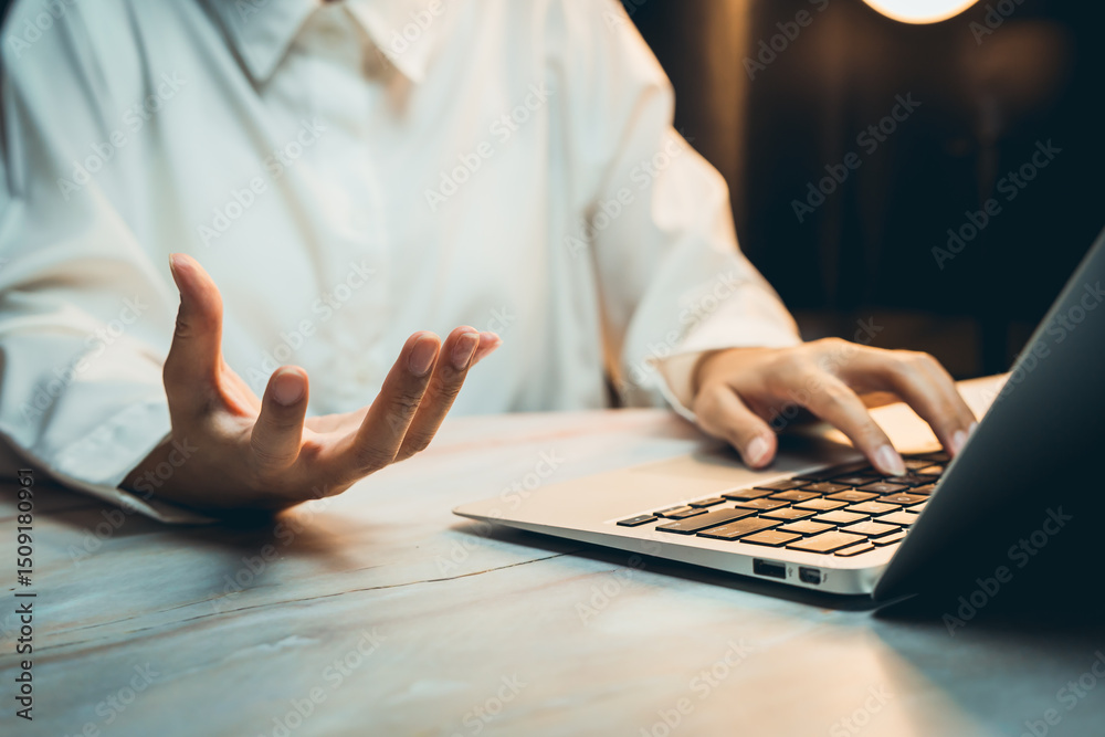 Fototapeta premium Business concept of working, Person in White Shirt Gesturing While Using Laptop at Home Office with Warm Lighting and Relaxed Atmosphere