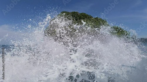 A boat moving quickly on clear waters near Phuket with frothy waves and a distant island in the background.