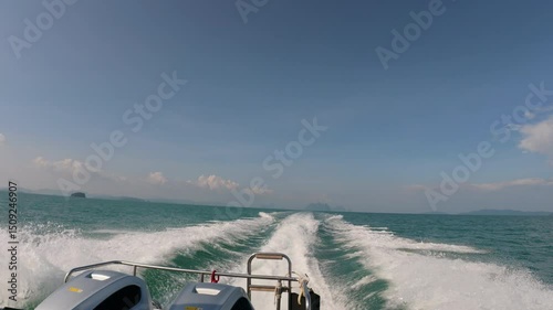 A boat moving quickly on clear waters near Phuket with frothy waves and a distant island in the background.