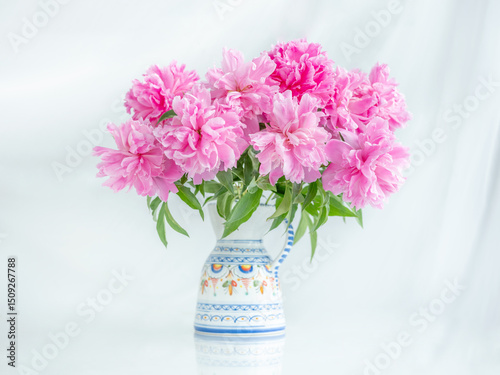 view to bouquet of pink peonies in vase on table in high key