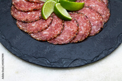 Portion of salami on black stone plate